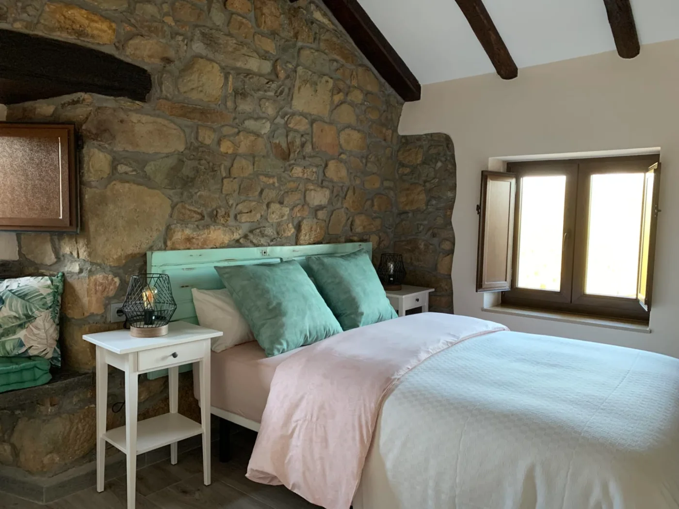 Dormitorio con cabecero de piedra y cojines verdes