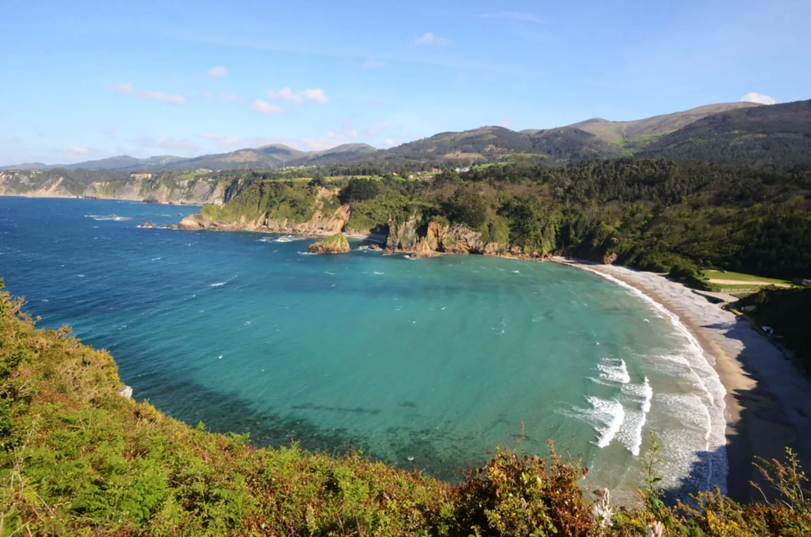 Playa de arena entre acantilados verdes